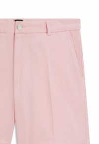 Pale pink trousers made of textured fabric, featuring a button closure, side pockets, and a tailored cut with straight legs.