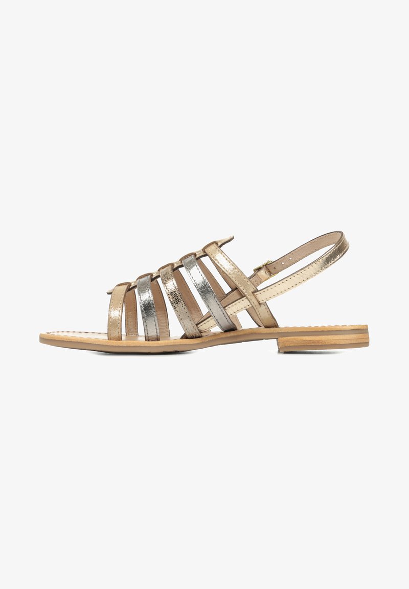 Sandale à brides avec des accents métalliques dorés et argentés, semelle plate, bout ouvert et une bride à la cheville à l'arrière. Texture lisse et semelle en bois.