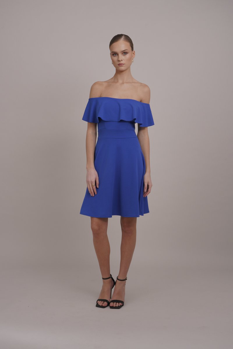 Vestido azul sem mangas com corpete com babados, cintura ajustada e saia rodada; combinado com saltos pretos com tiras.