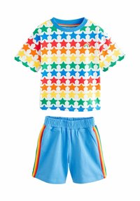 Camisa de manga corta en blanco con un estampado de estrellas multicolores; pantalones cortos azules con rayas de arcoíris a los lados. Tejido suave, cinturilla elástica.