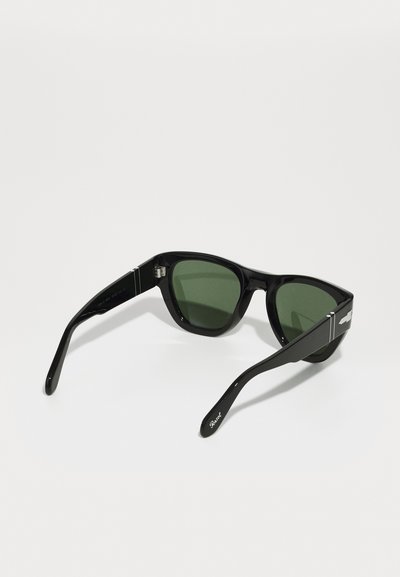 Čierne slnečné okuliare so zelenými sklami, obdĺžnikový tvar, lesklý plastový rám, strieborný akcent na spánkoch a zakrivené ramienka.