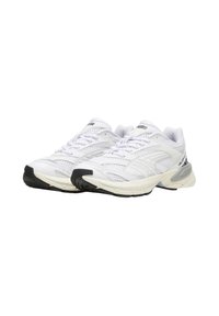 Weiße Sportschuhe aus Mesh- und Synthetikmaterialien, mit einer gepolsterten Sohle, weißen Schnürsenkeln und schwarzen Gummielementen.