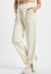 Cremefarvede sweatpants med afslappet pasform, elastisk talje, sidelommer og broderet detalje. Blødt stof og lige snit design.
