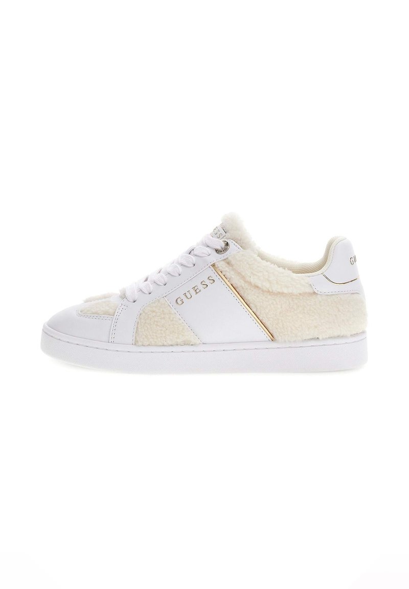 White sneaker featuring a plush, cream-colored shearling panel, gold accent, and white laces. Smooth texture with a round toe design.