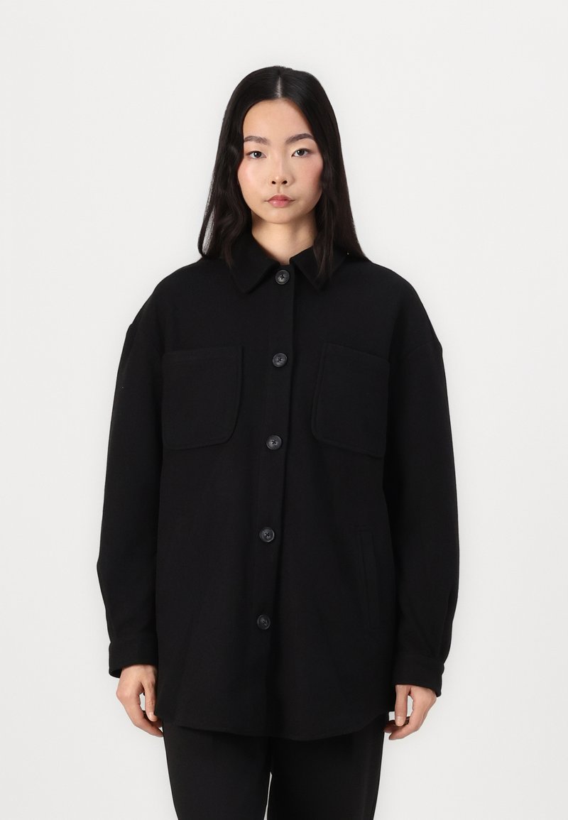 Zwarte wollen mix oversized jas met een kraag, frontsluiting met knopen, twee borstzakken en zijnaad. Soepele textuur en minimalistisch ontwerp.