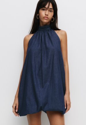Navy halter dress with gathered neck design, loose fit, and soft denim texture, featuring sleeveless shoulders and a flowy shape.