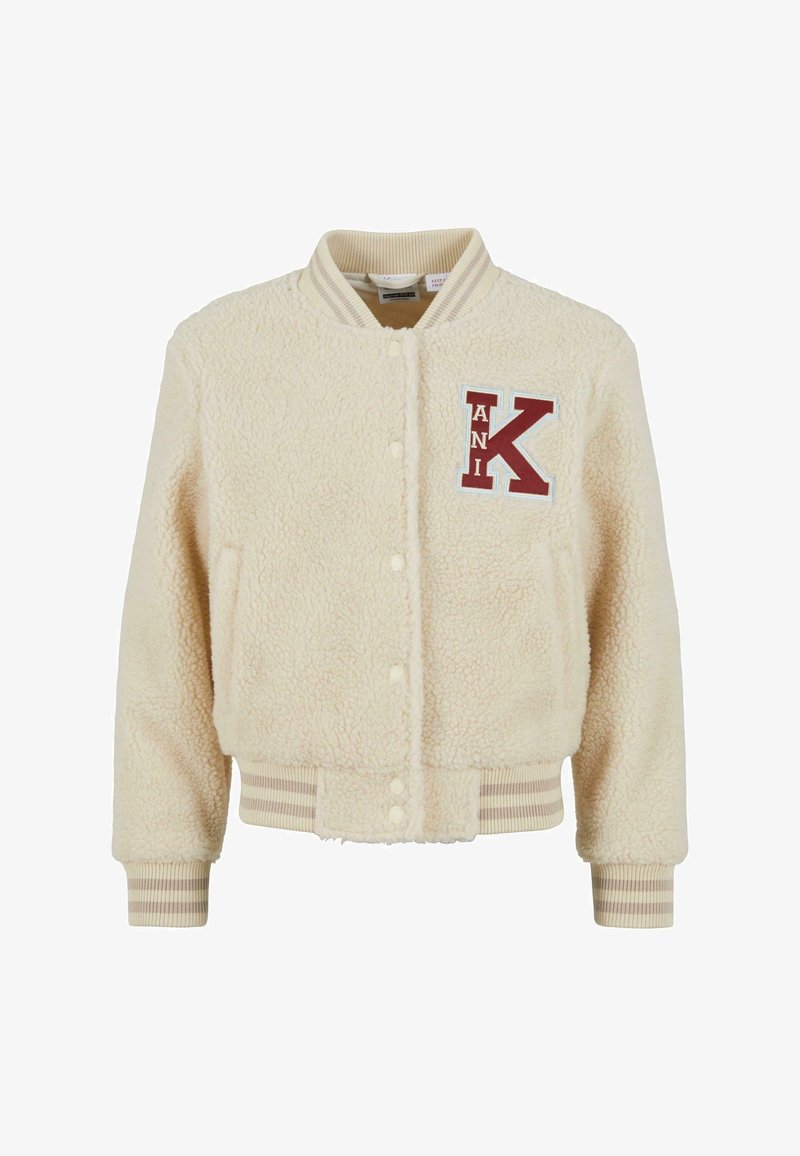 Fløjlsjakke i cremelignende farve med ribstrikket krave og ærmekanter. Indeholder et rødt og blåt broderet "KANI"-logo på brystet. Knappelukning.