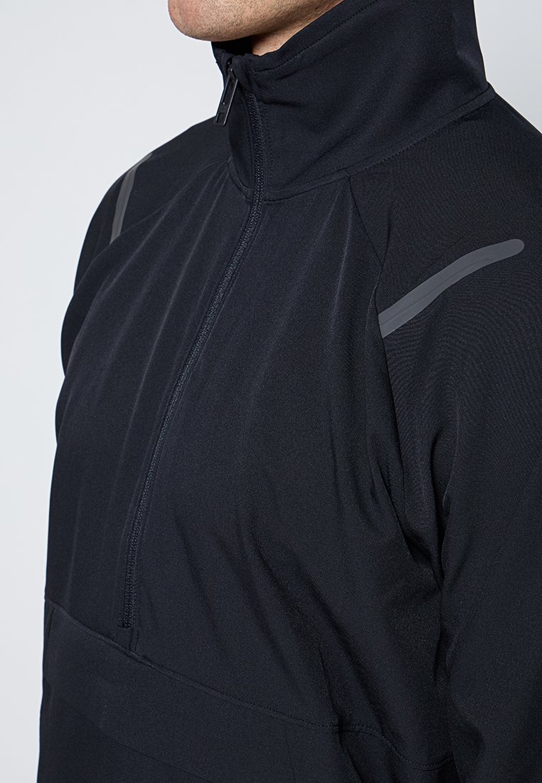 Veste à col montant noire avec fermeture zippée mi-longue, tissu texturé et accents gris réfléchissants aux épaules.