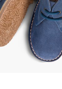 Pantofi azul cu sole de cauciuc texturat maro, având margine cusută și șireturi albastre asortate.