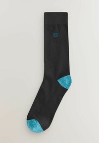 Mustat sukat, joissa on resorimainen rakenne, kirkkaan turkoosit yksityiskohdat kantapäällä ja varpaassa. Yläosassa pieni turkoosi logo.