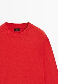 Roter Wollpullover mit rundem, geripptem Ausschnitt. Verfügt über eine glatte Textur und überschnittene Schulternähte. Das Etikett innen gibt eine 100 % Wollzusammensetzung an.
