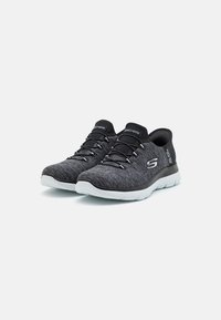 Scarpe da atletica nere e grigie con tomaia in tessuto testurizzato, lacci elastici, suola imbottita e suola in gomma bianca. Logo sul lato.