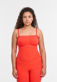 Červený bezešvý body s nastavitelnými ramínky; přiléhavý design s hladkou texturou a bez viditelných švů; minimalistický styl.