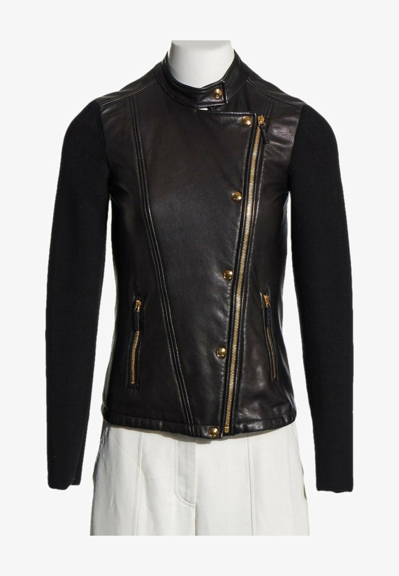 Veste en cuir noire avec fermetures éclair et boutons dorés, manches longues en tissu tricoté, et fermeture éclair asymétrique devant sur un mannequin.