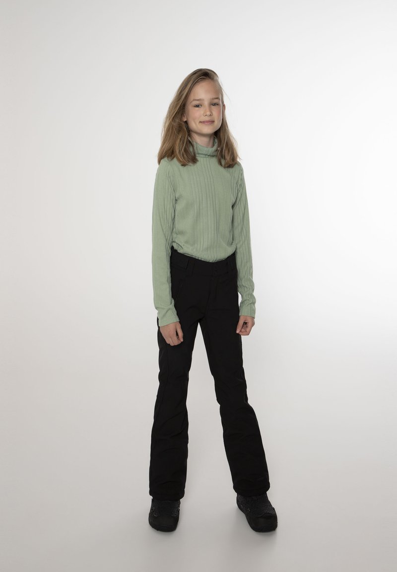 Maglia a maniche lunghe ribassata verde chiaro, pantaloni da sci neri e stivali neri. La maglia ha un collo alto e maniche aderenti, mentre i pantaloni sono a gamba dritta.