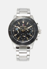 Silberner Edelstahl-Uhr mit schwarzem Zifferblatt, goldenen Akzenten, Chronographen-Subdials und einer schwarzen Lünette, ausgestattet mit einem Gliederarmband.