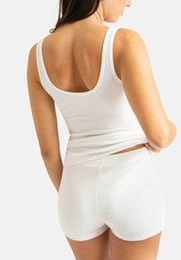Débardeur blanc côtelé et shorts assortis, présentant un design ajusté avec de larges bretelles et une texture lisse, vus de derrière.