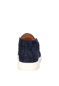 Marineblauwe suède sneaker met een gestructureerde afwerking, voorzien van een contrasterende witte rubberen zool en minimalistische stiksels aan de achterkant.