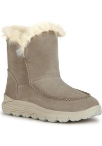 Botas de tobillo de ante color marrón con borde de pelo sintético, costuras decorativas y suela texturizada ligera. Presentan una puntera redondeada y un tacón ligeramente elevado.