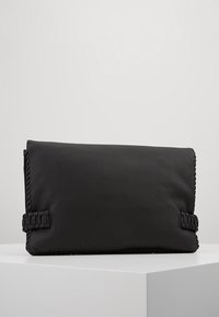 Clutch bag in pelle nera con superficie testurizzata, caratterizzata da accenti laterali intrecciati e forma rettangolare. Design minimalista, stile chiuso.