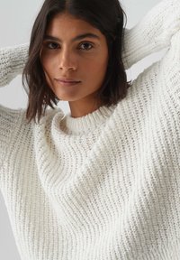 Maglione bianco a maglia texturizzata con una vestibilità ampia, con scollo rotondo e dettagli a coste sulle maniche e sul bordo.