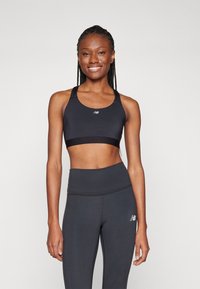 Soutien-gorge de sport noir et leggings taille haute en tissu extensible. Présente un design dos nageur et un petit logo sur le soutien-gorge.
