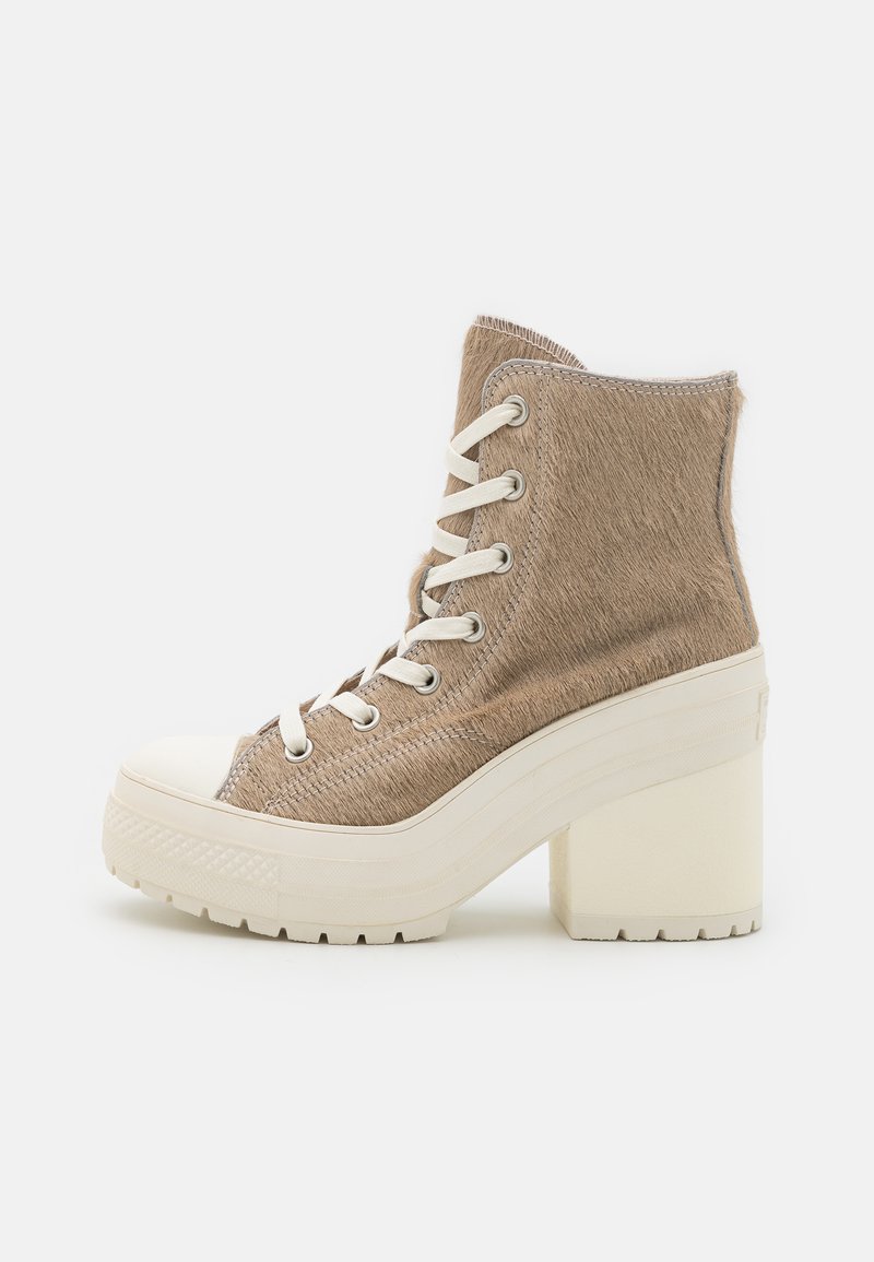 High-top platform sneakers featuring a beige textured upper, white rubber toe cap, and chunky white block heel with lace-up design.