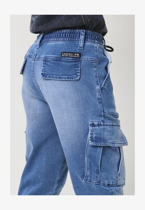 Világoskék farmer cargo nadrág, rugalmas derékkal, oldalsó zsebekkel és hátsó foltlogóval. Texturált, laza szabású dizájn.