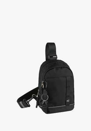 Kompakt sort crossbody taske med justerbar skulderrem, frontlomme med lynlås og nøglering på hvid baggrund.