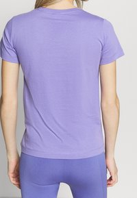 Lila kortärmad t-shirt, mjukt bomullsmaterial, rund halsringning, figursydd form, rak fåll, slät textur, minimal sömdetalj.