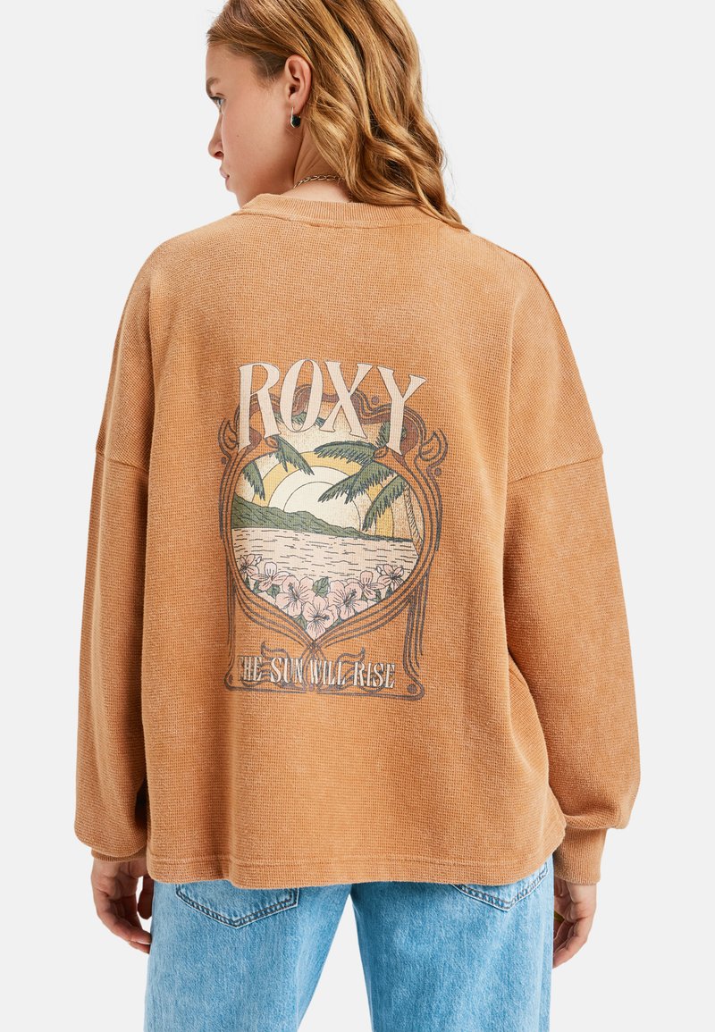 Pudrowo-różowy, oversize'owy sweatshirt wykonany z teksturowanej tkaniny, z grafiką przedstawiającą palmy i kwiaty na plecach.