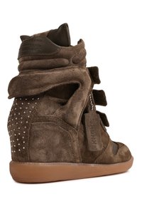 Καφέ σουέτ αθλητικό παπούτσι με σφήνα, τακούνι με τρουκς, λουράκια βέλκρο και ετικέτα σουέτ στο ίδιο χρώμα σε λευκό φόντο.