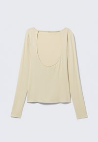 Μπεζ μπλούζα με μακριά μανίκια και μεγάλο στρογγυλεμένο τετράγωνο άνοιγμα στο πίσω μέρος, φτιαγμένη από απαλό, ελαφρύ ύφασμα.