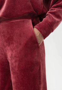 Cranberry fluwelen lounge set met een relaxte pasvorm. De top heeft een gebogen zoom en de broek heeft zijzakken met een zachte textuur.