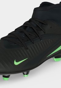 Μαύρο ποδοσφαιρικό παπούτσι Nike με λογότυπα Swoosh σε νέον πράσινο χρώμα και ακρωνύχια, με υφασμάτινο συνθετικό επάνω μέρος και μαύρα κορδόνια.