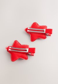 Red star-shaped hair clips with a textured finish, featuring metal clips and bright fabric. Two clips positioned side by side.
