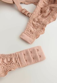 Podprsenkový ramienok svetloružovej farby s čipkovanou ozdobou, nastaviteľnou kovovou sponou a zapínaním na háčiky s tromi háčikmi na úpravu veľkosti.