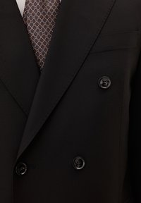 Zwarte dubbelgeknoopte suitjack met glanzende zwarte knopen, scherpe revers en een getailleerd ontwerp. Draagt een gestreepte bruine stropdas.