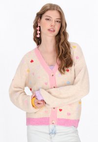 Cardigan bej pufos cu modele colorate de inimi, decolteu în V roz și nasturi, având o margine roz cu dantele și manșete cu un gradient curcubeu.