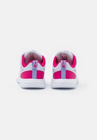 Un par de zapatillas Nike Revolution blancas y rosas vistas desde atrás, con forro de malla y suelas texturizadas blancas sobre un fondo blanco.