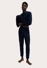 Conjunto de ropa cómoda de algodón azul marino que incluye una camiseta de manga larga y pantalones ajustados con cordón. Textura suave y ajuste relajado.