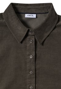 Koszula z kordurojowej tkaniny w oliwkowym kolorze z klasycznym kołnierzykiem, zapinana na guziki, z teksturowanym materiałem. Metka z napisem "CECIL." Posiada pięć guzików.