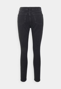 Jeans skinny negros con una cintura de medio tiro, que cuentan con dos bolsillos traseros y una textura de denim suave y ligeramente elástica. Sin bolsillos frontales visibles.
