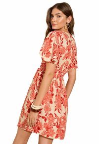 Rochie florală crem cu model floral roșu. Mâneci scurte, talie elastică, lungime deasupra genunchiului. Material neted, design casual.