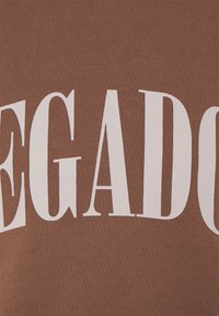 T-shirt in cotone marrone con tipografia bianca audace. Il tessuto è morbido con una texture sottile, che enfatizza il design delle lettere.