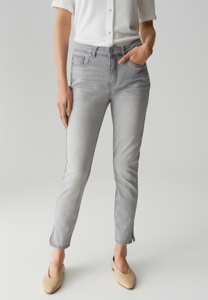 Jeans grigi chiari con una vestibilità slim, dotati di chiusura con bottone e zip, tasche anteriori e sottili spacchi laterali all'orlo.