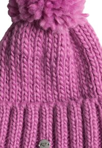 Pink knitted beanie with a textured ribbed pattern, topped with a fluffy pom-pom. Features a small silver accent tag on the knit.