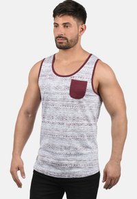 Herre tank topp i lys grå med burgunder detaljer. Har en lomme og et geometrisk mønster over hele. Laget av bomull med en avslappet passform.