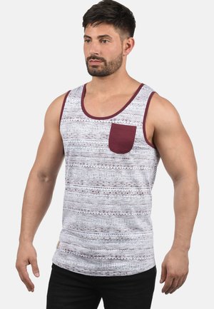 Herretanktop i lys grå med maroon detaljer. Har en lomme og et geometrisk mønster over det hele. Lavet i bomuld med en afslappet pasform.