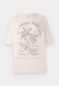 T-shirt en coton beige clair à manches courtes, avec un graphique de palmiers et une figure sur le devant, le texte indique "Encore un jour au paradis."